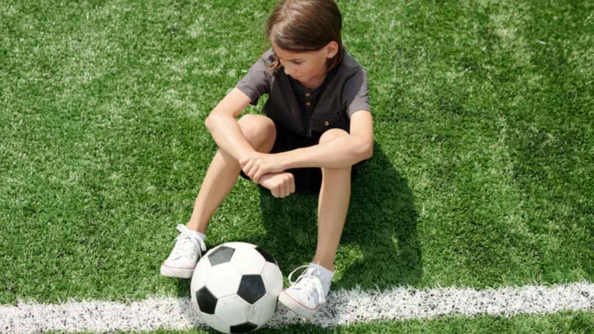 youth-soccer-ball Young child sitting alone on a soccer filed with a soccer ball
