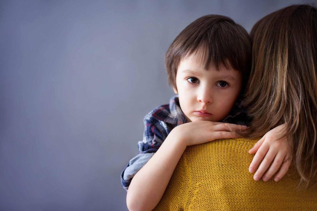 A woman holding a young boy with an anxious look