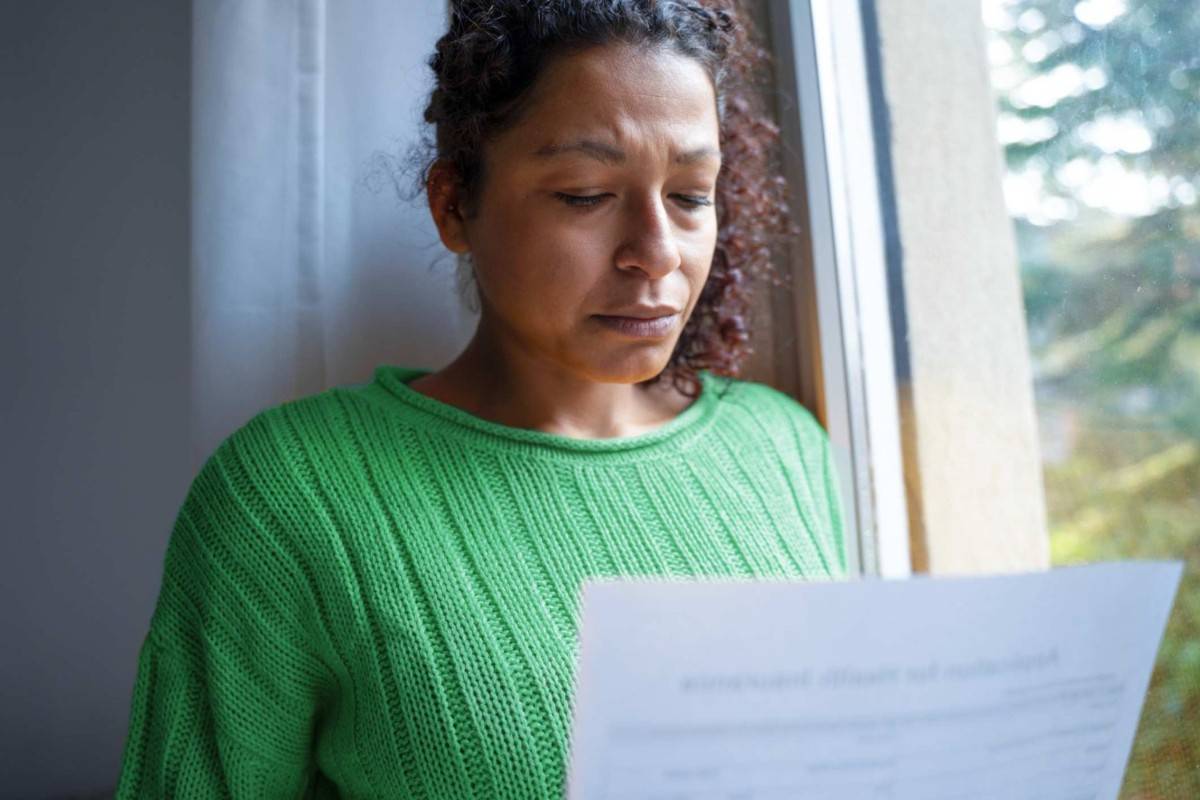 Woman with a worried look standing next to a woman reading paperwork