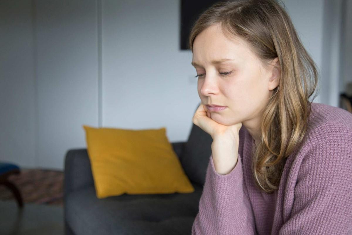 A young woman sitting on a couch with a look of concern