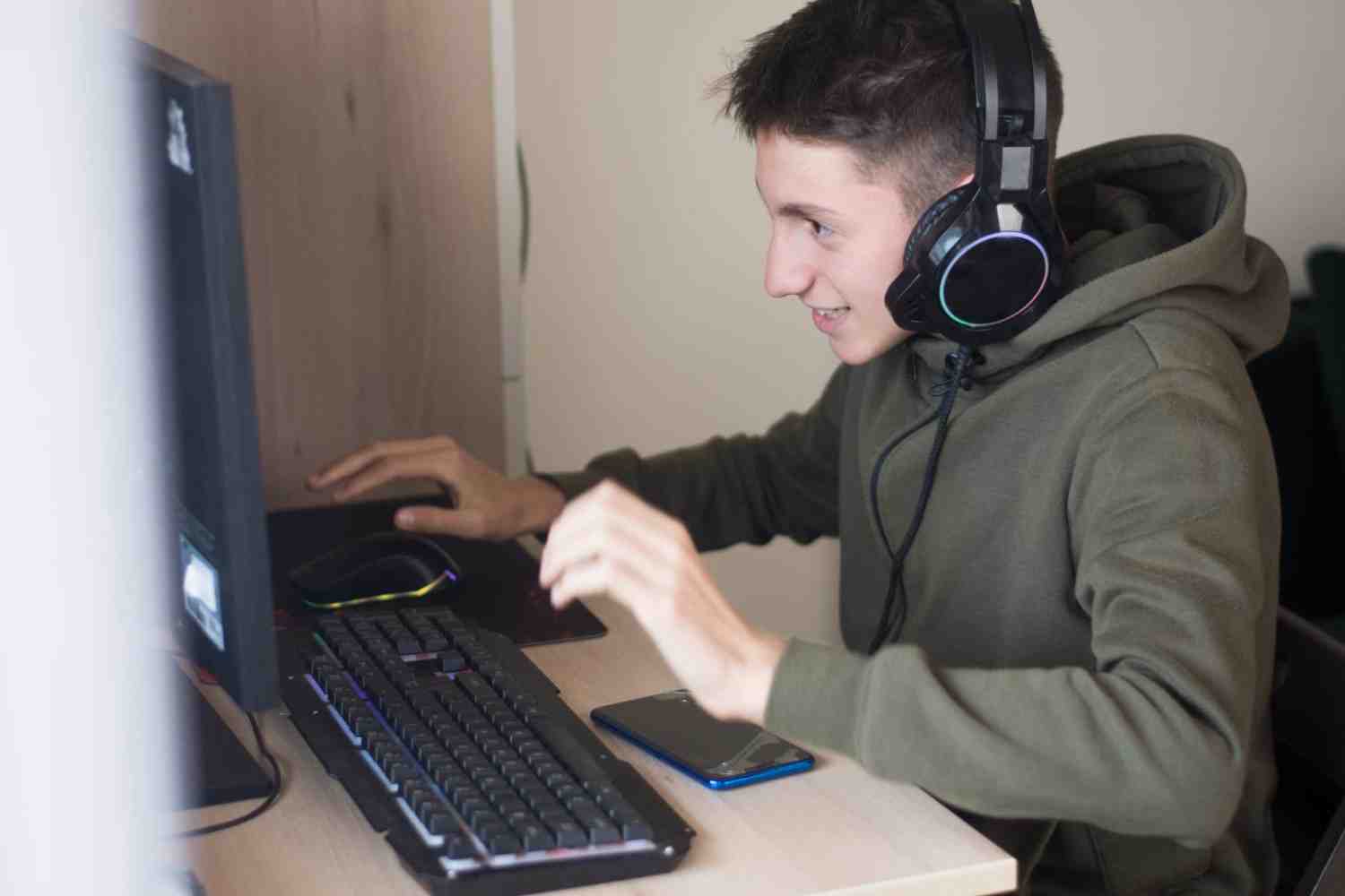 Teen wearing headphones and playing games on his computer.