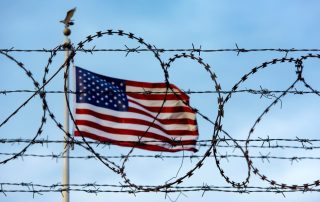 American flag flying behind barbed wire