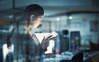 Woman in an office at night looking at a digital pad