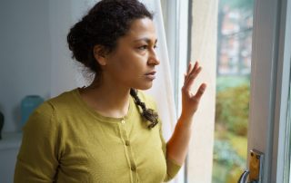 Woman standing at window and glaring outside
