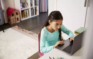 A young girl in her room working on her laptop