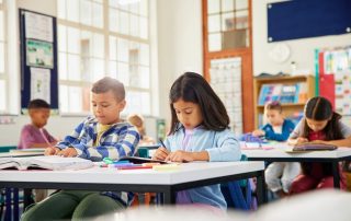 Elementary school aged children sitting at their desks in a classroom doing school work