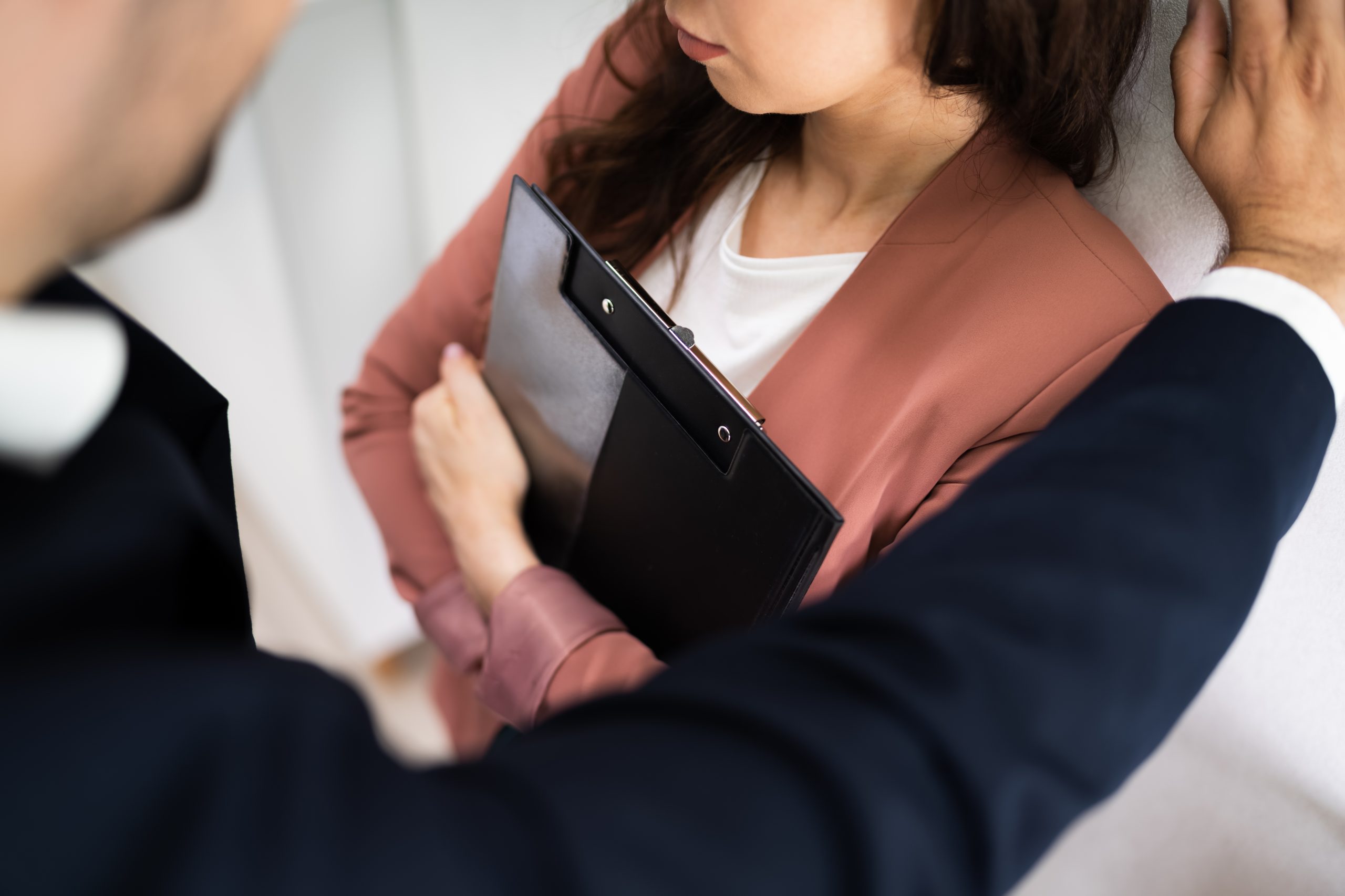 Woman backed up against a wall at work by a man in a dark suit.