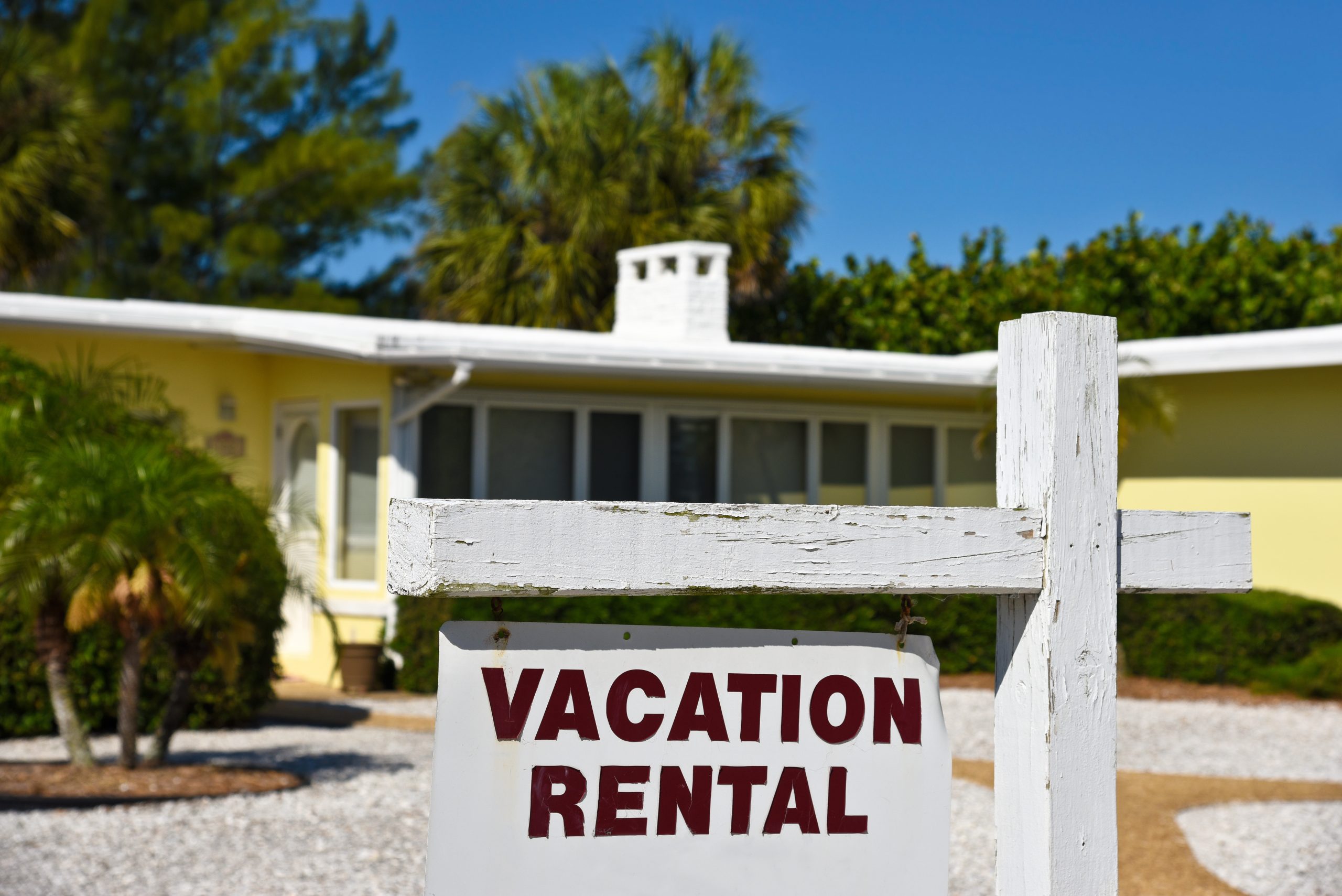 Yellow and white home with a Vacation Rental sign hanging in front of the property.