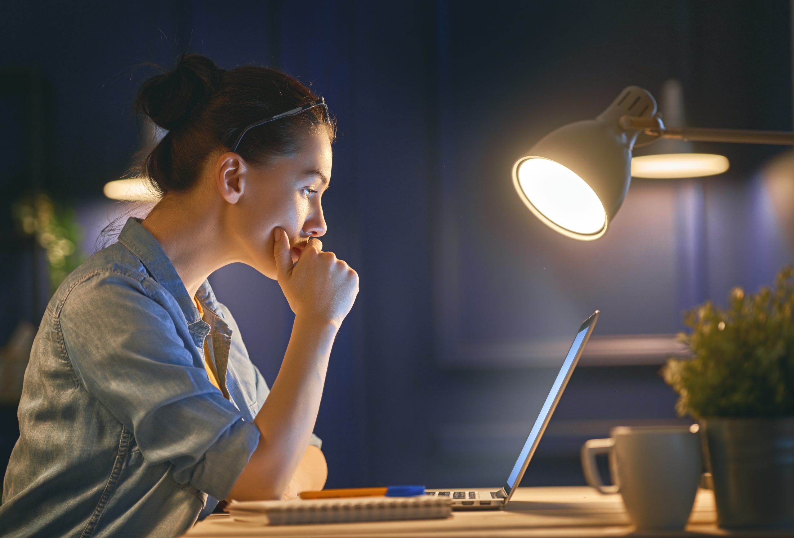Woman working on a laptop at night alone in an office.
